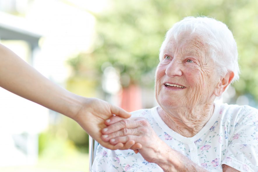 jemand reicht einer älteren Dame helfend die Hand.